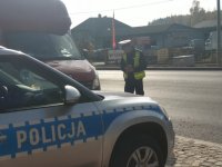 policjant WRD KPP Mońki podczas kontroli drogowej sprawdzający stan oświetlenia pojazdu