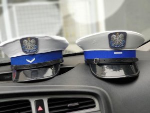 czapki policjantów RD na kokpicie radiowozu