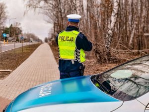 sylwetka policjanta mierzącego prędkość pojazdów