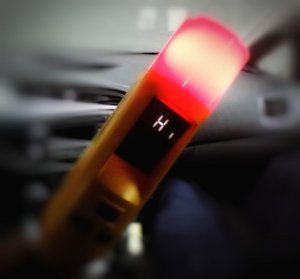 AlcoBlow z zapaloną lampką koloru czerwonego, w tle wnętrze pojazdu