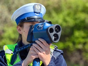 na zdjęciu twarz policjantki zasłoniętej miernikiem prędkości