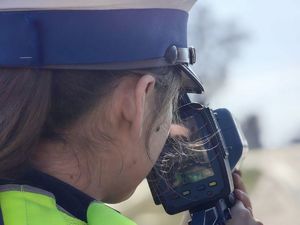 na zdjęciu twarz policjantki odwróconej tyłem z urządzeniem do pomiaru prędkości